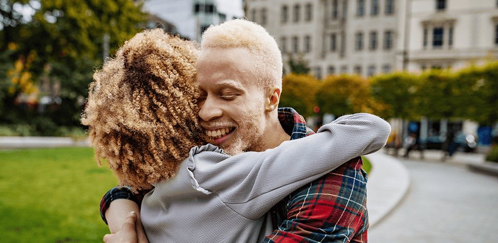 A couple embracing outside a train station, they're both happy because they have not seen each other for a long time. This demonstrates the positive 33 per cent saving by using the Network Railcard for usage across London and the south east. 